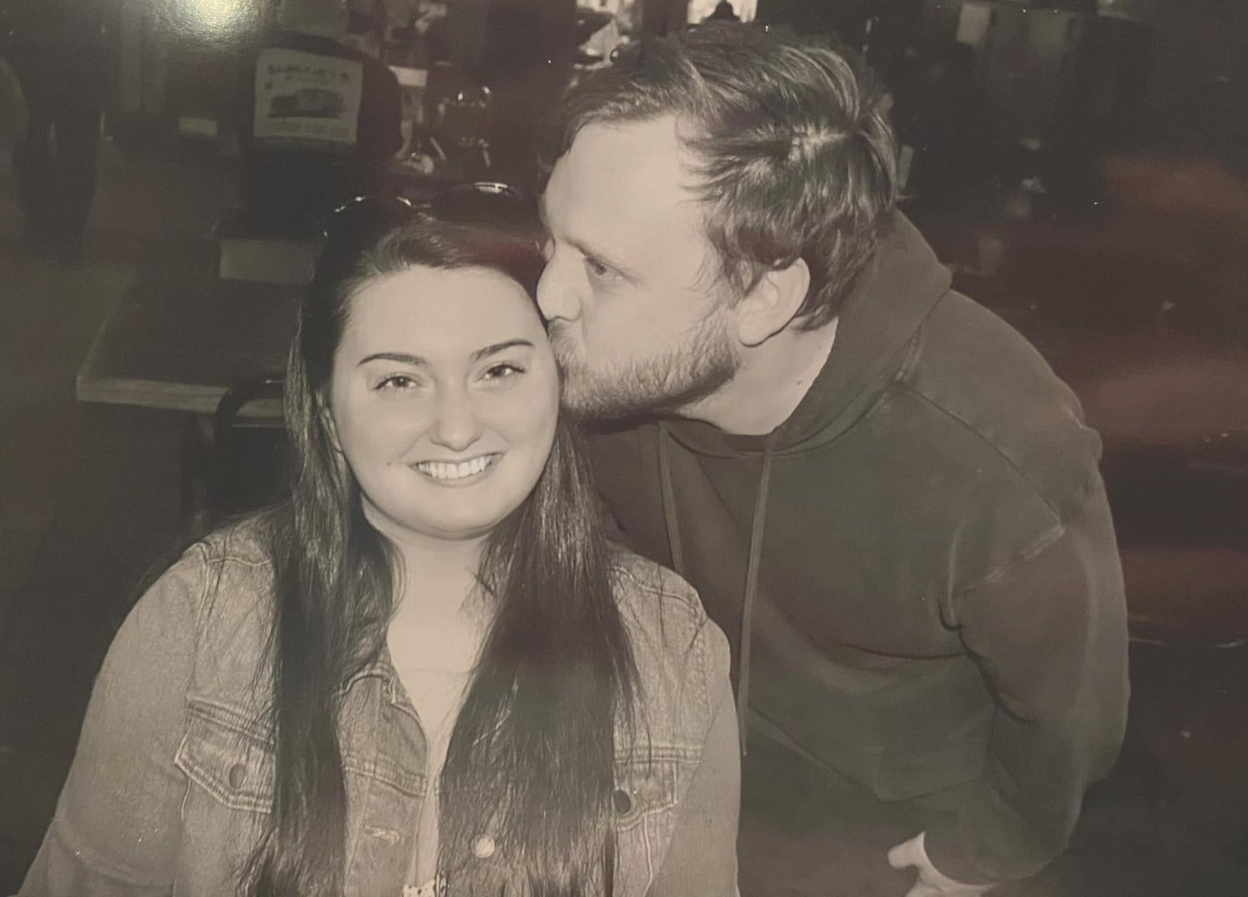 Louis kissing Cassie on the forehead at a bar